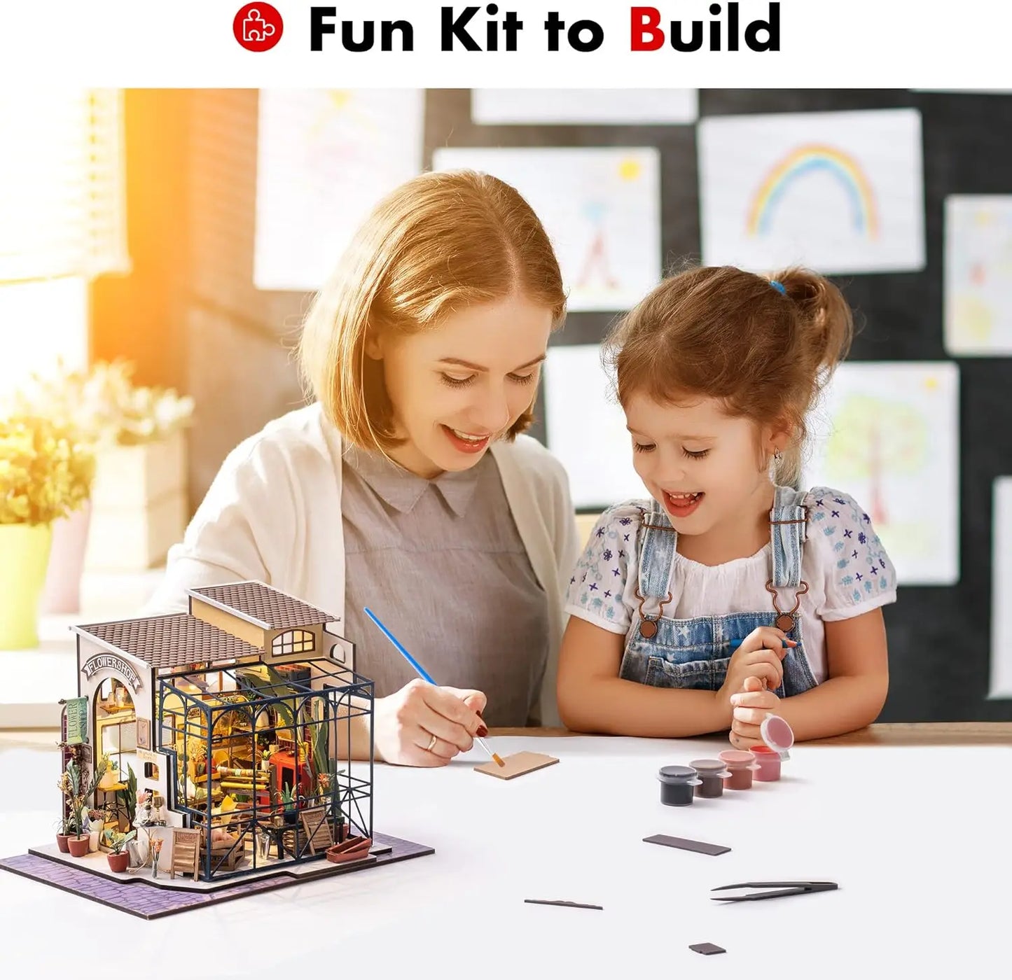 Mother and daughter building a miniature house kit at a table, craft paints and tools visible