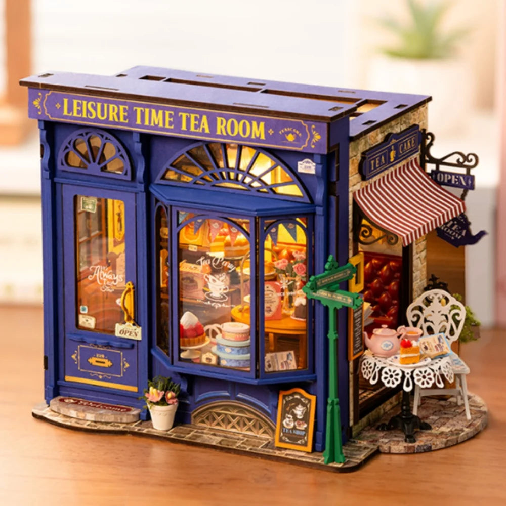 Miniature blue tea room model with tea set, pastries, and outdoor table display